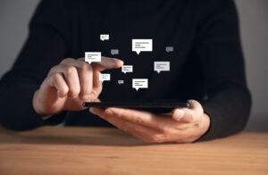 A man is seen holding a tablet attempting to choose one of the hovering illustrations that depict SMS and serve as representations of SMS templates