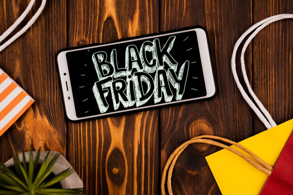 An iphone on top of a wooden table which shows in a blackboard style an illustration of the heading BLACK FRIDAY